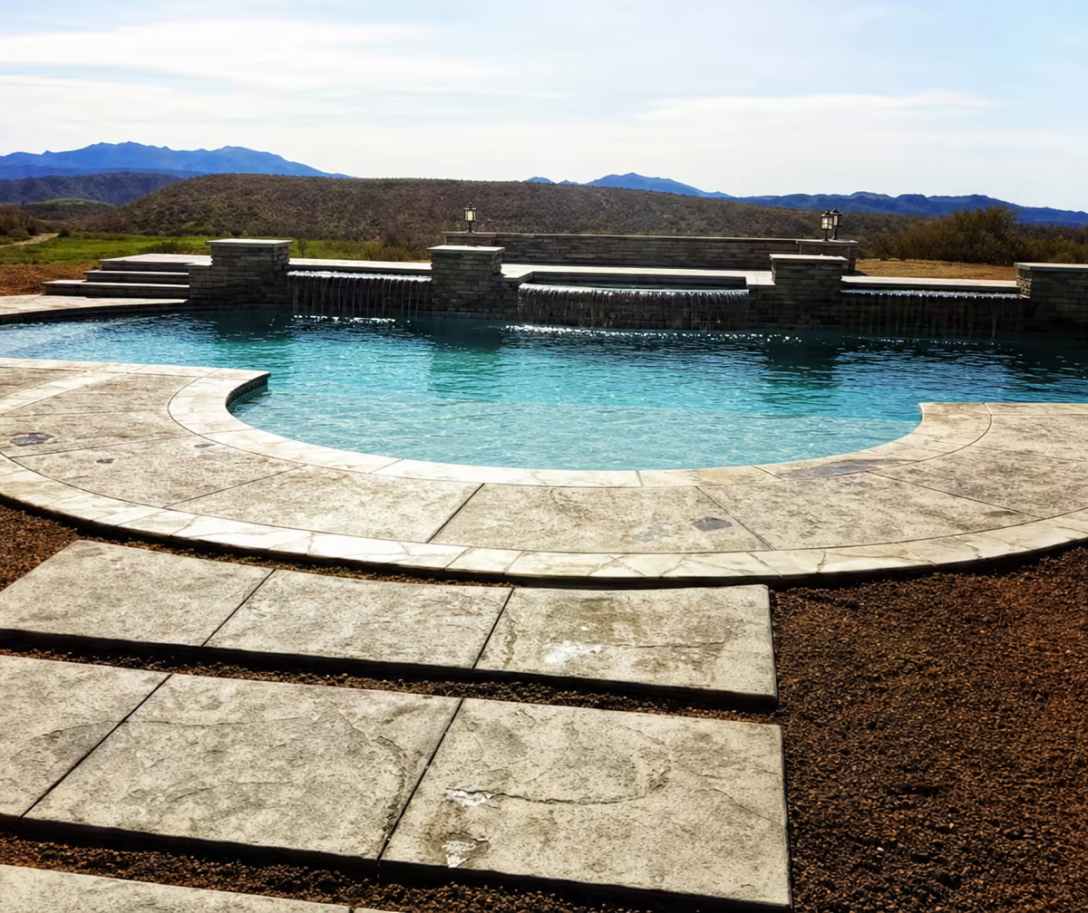 Curved pool with stamped concrete paths and mountain views